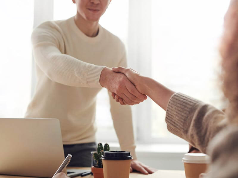 Two business professionals shaking hands in a meeting.
